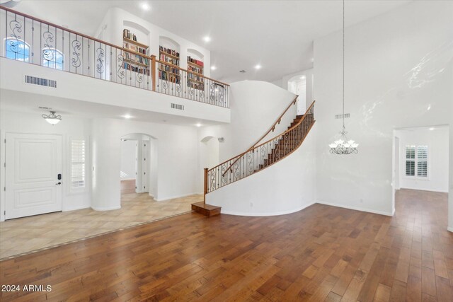 entryway featuring hardwood / wood-style flooring, a towering ceiling, and a notable chandelier