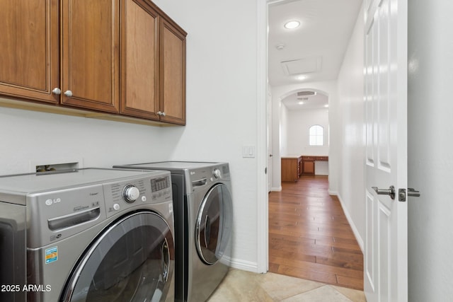 laundry area featuring cabinets, washing machine and dryer, and light wood-type flooring