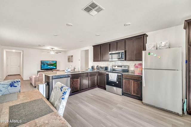 25787 W Allen St, Buckeye, AZ 85326 - kitchen featuring stainless steel appliances, dark brown cabinetry, open floor plan, a sink, and tasteful backsplash