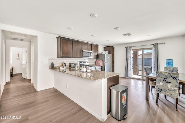 25787 W Allen St, Buckeye, AZ 85326 - kitchen with appliances with stainless steel finishes, light wood finished floors, dark brown cabinets, light stone countertops, and tasteful backsplash
