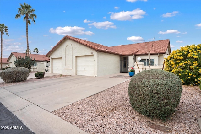 view of front of house with concrete driveway, a tiled roof, an attached garage, and stucco siding