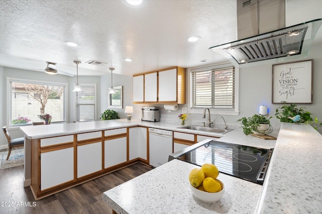 kitchen with visible vents, a peninsula, white dishwasher, a sink, and light countertops