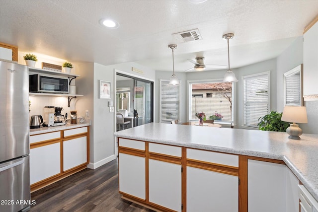 kitchen with visible vents, dark wood-style flooring, stainless steel appliances, light countertops, and white cabinetry