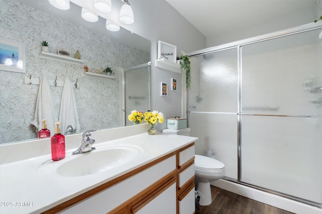 bathroom with toilet, vanity, wallpapered walls, and a shower stall