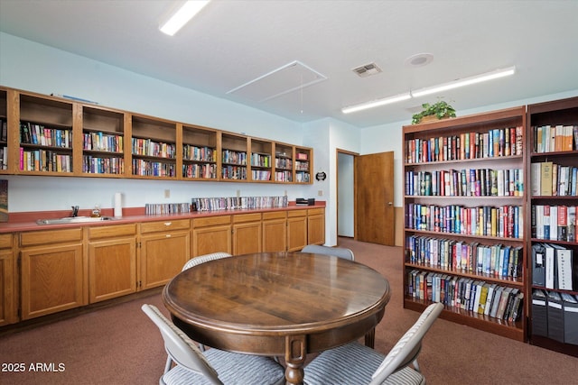 interior space featuring attic access, carpet flooring, visible vents, and bookshelves