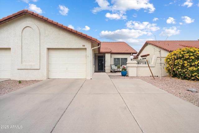 mediterranean / spanish home with a garage, concrete driveway, stucco siding, and a tile roof