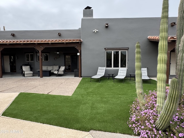 rear view of house with an outdoor living space, a patio, and a lawn