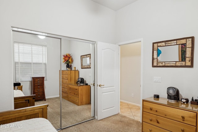 bedroom featuring light carpet, a closet, and a high ceiling