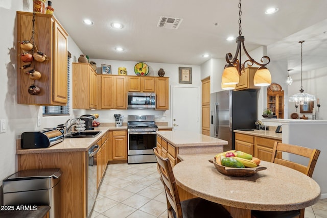 kitchen featuring appliances with stainless steel finishes, sink, decorative light fixtures, a notable chandelier, and a kitchen island