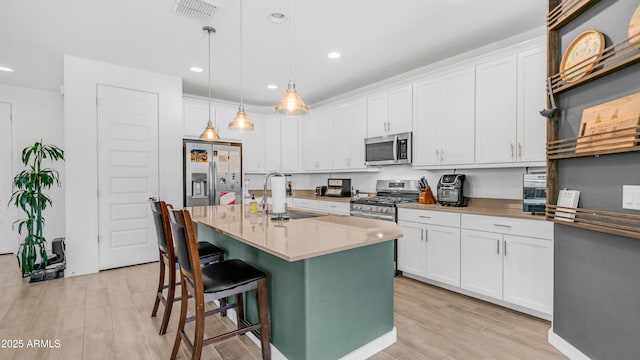 3117 E Hayfield Way, San Tan Valley, AZ 85140 - kitchen featuring a sink, stainless steel appliances, light wood-style floors, a breakfast bar area, and white cabinetry