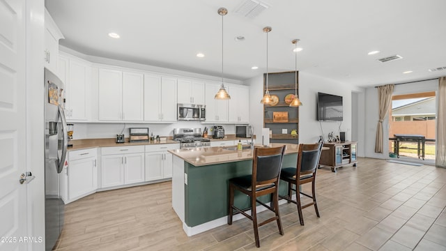 3117 E Hayfield Way, San Tan Valley, AZ 85140 - kitchen with appliances with stainless steel finishes, white cabinetry, a kitchen breakfast bar, pendant lighting, and an island with sink