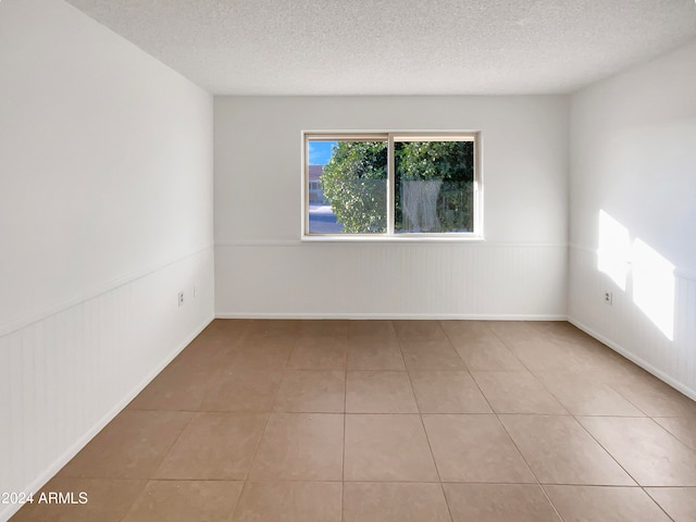 tiled empty room with a textured ceiling