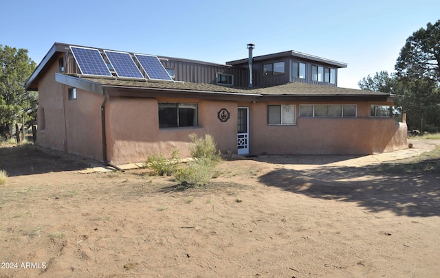 rear view of property with solar panels