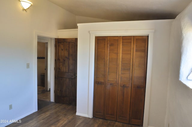 unfurnished bedroom with lofted ceiling, dark wood-type flooring, and a closet