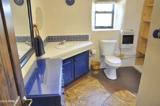 bathroom with heating unit, vanity, and toilet