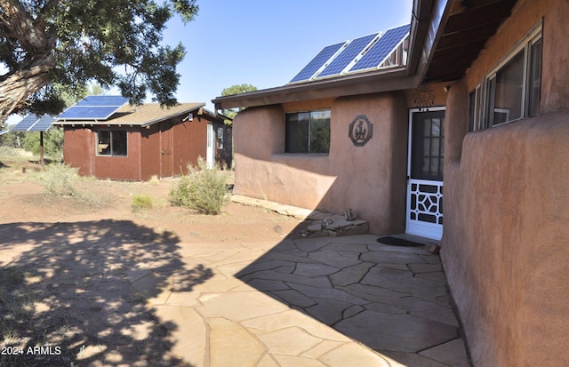 view of home's exterior featuring solar panels, a shed, and a patio area