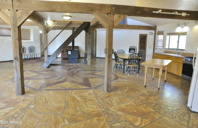 dining area featuring sink and lofted ceiling with beams