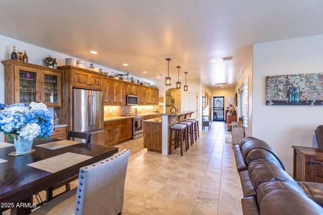 965 Calle Azul, Wickenburg, AZ 85390 - kitchen featuring appliances with stainless steel finishes, a breakfast bar area, light stone counters, backsplash, and arched walkways