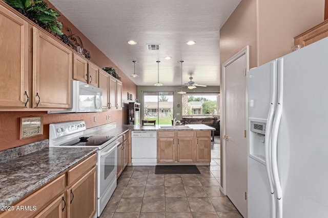 kitchen with visible vents, a sink, white appliances, a peninsula, and tile patterned floors