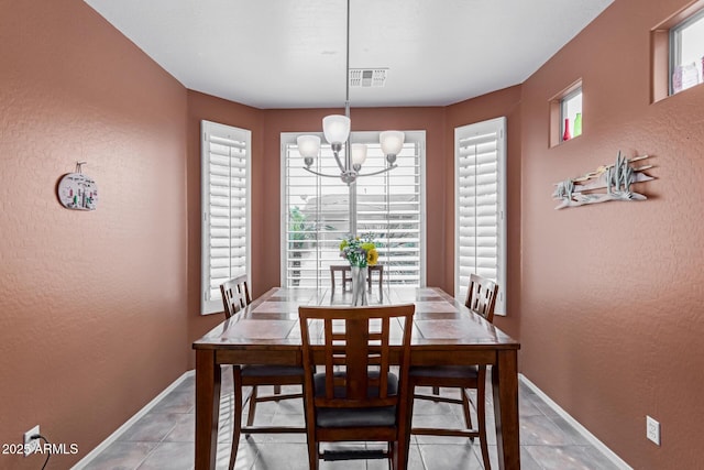 dining area featuring a notable chandelier, a textured wall, visible vents, and baseboards