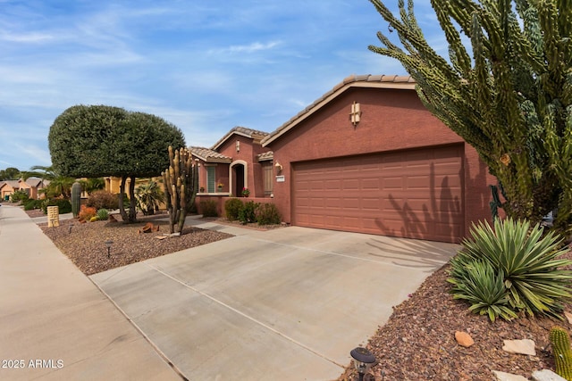 view of front facade featuring a garage, driveway, a tiled roof, and stucco siding