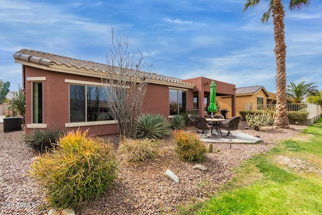 rear view of property featuring a patio, a tile roof, cooling unit, and stucco siding