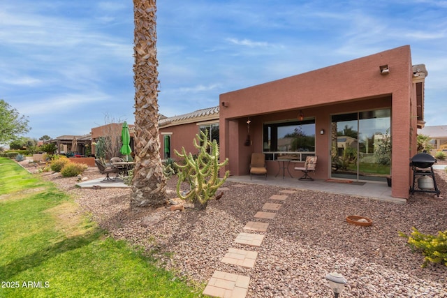 rear view of property featuring a patio and stucco siding