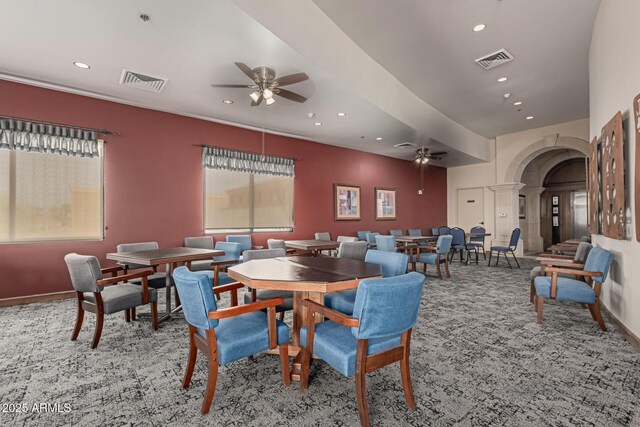 carpeted dining room featuring arched walkways, ceiling fan, and visible vents