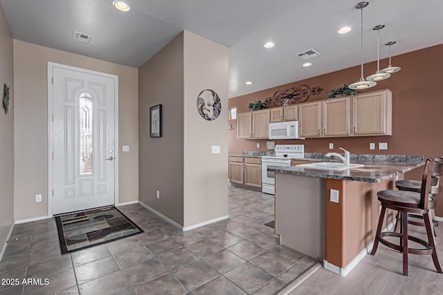 kitchen with a peninsula, white appliances, visible vents, and a sink