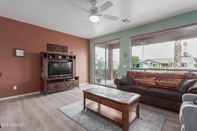 living area featuring a ceiling fan, visible vents, baseboards, and wood finished floors