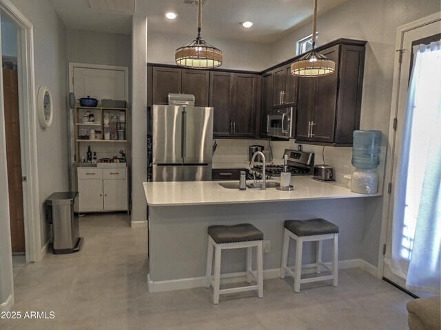 21696 E Arroyo Verde Dr, Queen Creek, AZ 85142 - kitchen featuring a peninsula, dark brown cabinets, light countertops, stainless steel appliances, and backsplash
