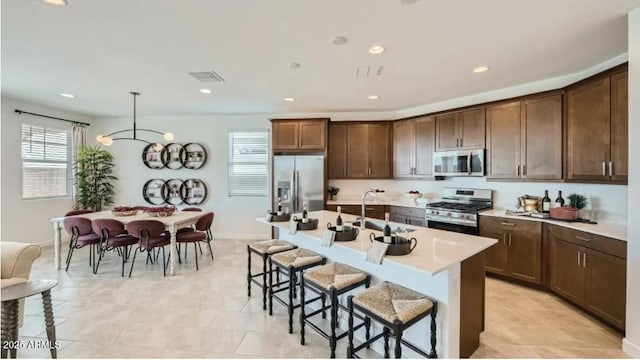 23081 E Saddle Way, Queen Creek, AZ 85142 - kitchen with stainless steel appliances, a sink, a kitchen breakfast bar, light countertops, and a center island with sink