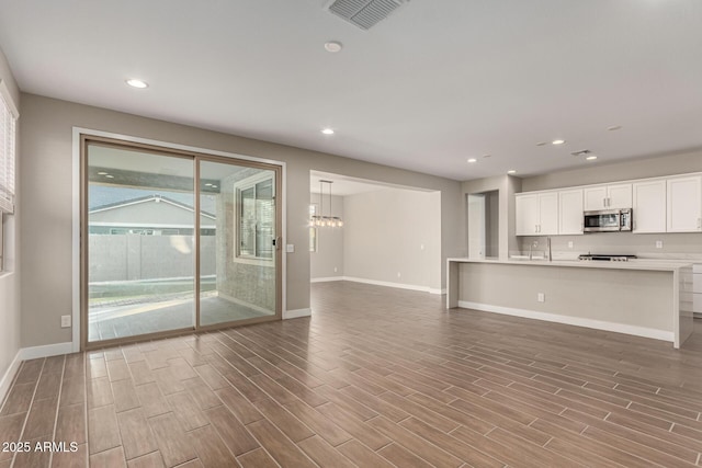 unfurnished living room featuring sink and a notable chandelier