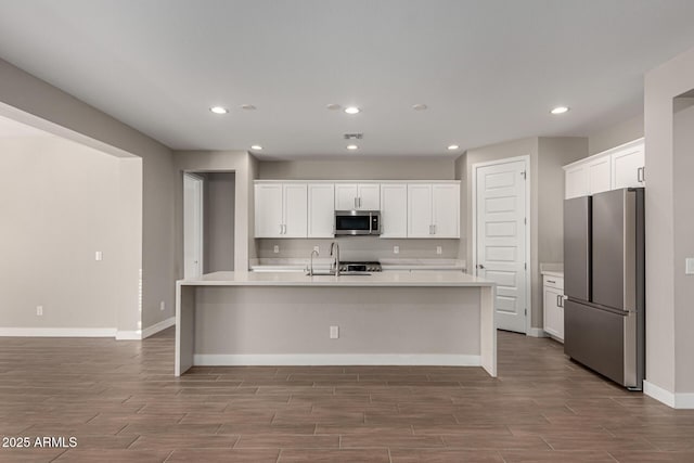 kitchen with sink, appliances with stainless steel finishes, an island with sink, and white cabinetry