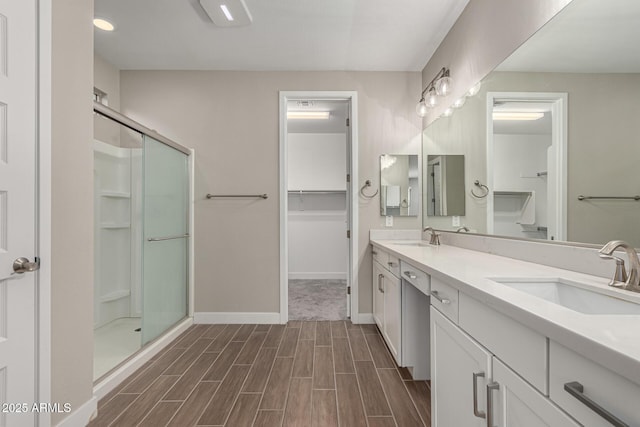 bathroom featuring a shower with shower door and vanity