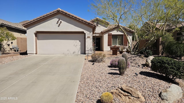 mediterranean / spanish house with fence, a tile roof, stucco siding, driveway, and an attached garage