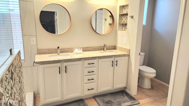 bathroom with tile patterned flooring, double vanity, toilet, and a sink