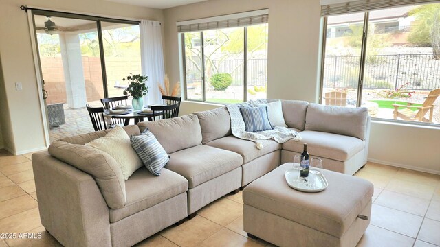 living room featuring light tile patterned floors, baseboards, and ceiling fan