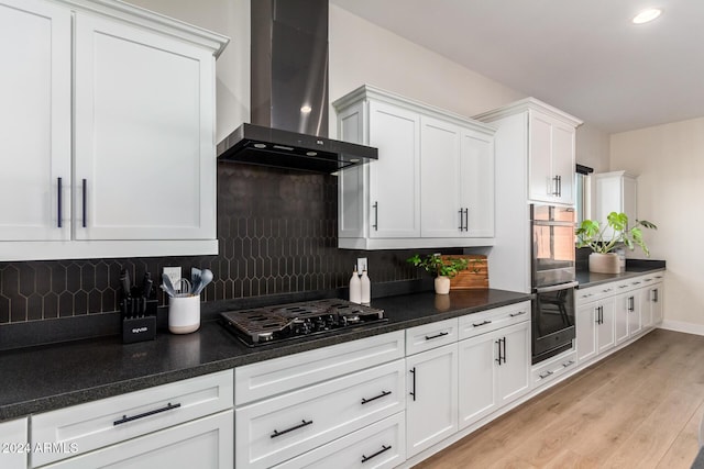 kitchen featuring decorative backsplash, wall chimney exhaust hood, black appliances, light hardwood / wood-style floors, and white cabinetry