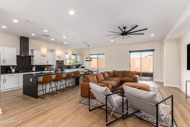 living room with light hardwood / wood-style flooring, ceiling fan, and sink