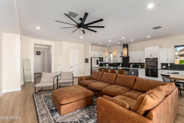 living room with light hardwood / wood-style floors and ceiling fan