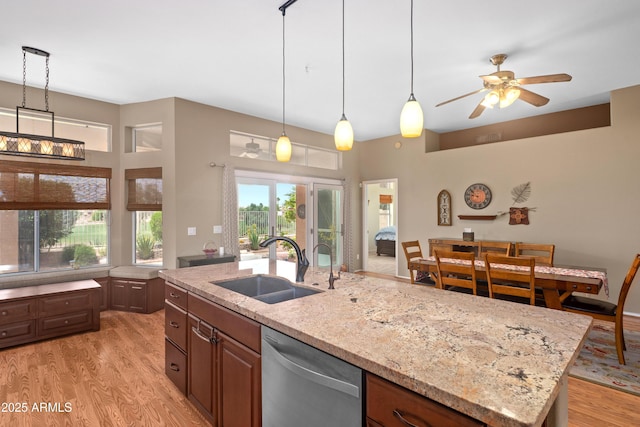 11553 W Cottontail Ct, Surprise, AZ 85378 - kitchen with dishwasher, a sink, light wood-style floors, a kitchen island with sink, and light stone countertops