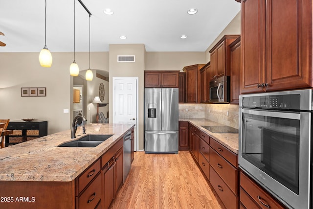 11553 W Cottontail Ct, Surprise, AZ 85378 - kitchen featuring stainless steel appliances, a sink, light wood-type flooring, a kitchen island with sink, and light stone counters