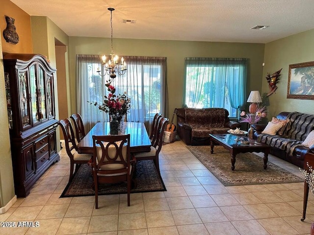 dining room featuring light tile patterned floors, a textured ceiling, and an inviting chandelier