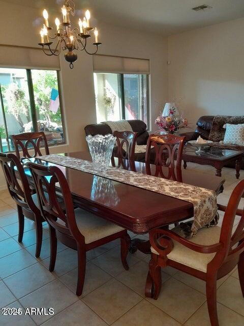 dining area with plenty of natural light, light tile patterned floors, and an inviting chandelier