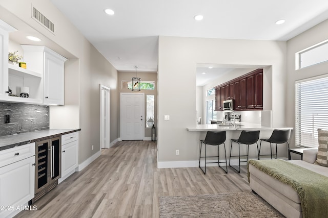 8848 E Conquistadores Dr, Scottsdale, AZ 85255 - kitchen featuring beverage cooler, stainless steel microwave, light wood-style floors, plenty of natural light, and recessed lighting