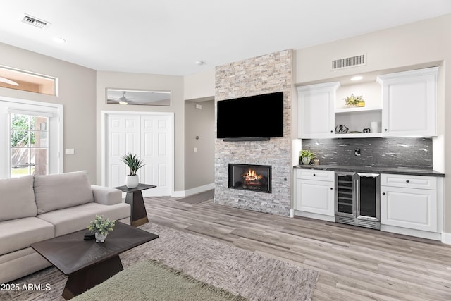 8848 E Conquistadores Dr, Scottsdale, AZ 85255 - living room featuring beverage cooler, light wood finished floors, a fireplace, and ceiling fan
