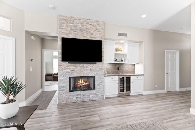 8848 E Conquistadores Dr, Scottsdale, AZ 85255 - living room with wine cooler, light wood-type flooring, a stone fireplace, and recessed lighting