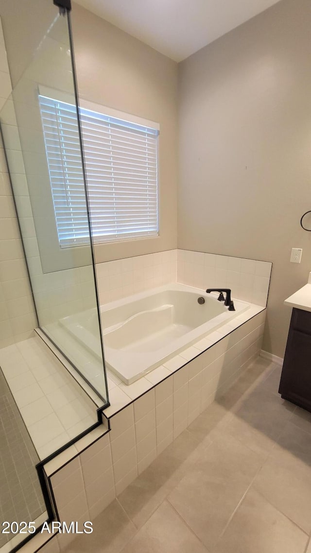 bathroom with tile patterned floors, tiled bath, and vanity