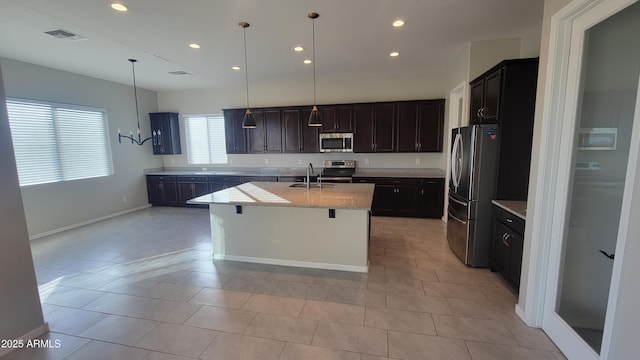 kitchen featuring dark brown cabinetry, sink, an island with sink, decorative light fixtures, and appliances with stainless steel finishes